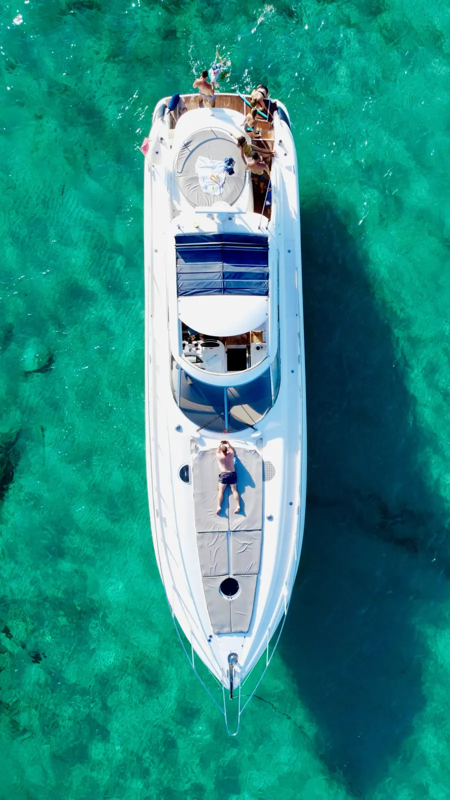 Aerial view of guests on a motor yacht in turquoise water
