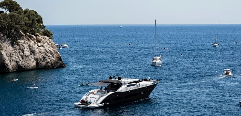 A yacht cruising past a Mediterranean coastline